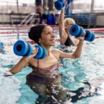 A woman in the water doing weight lifting exercises.