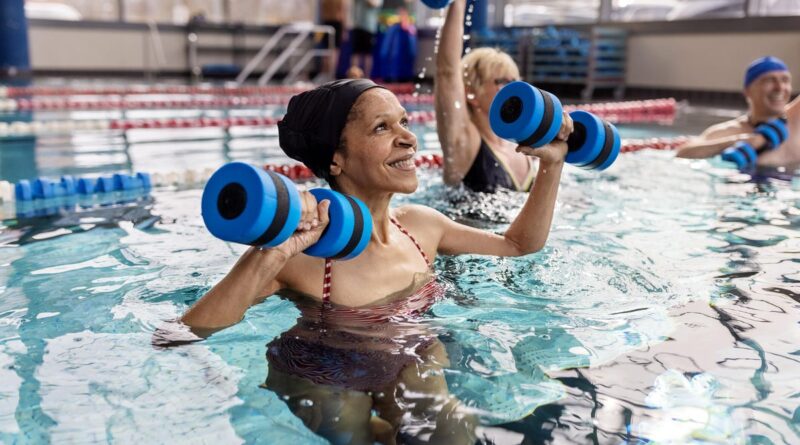 A woman in the water doing weight lifting exercises.